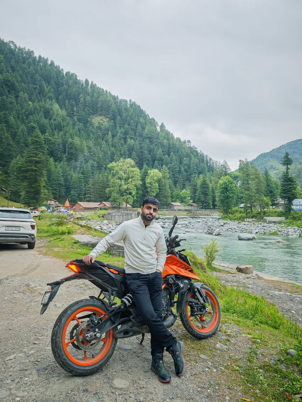 Sarthak beside his motorcycle in the mountains